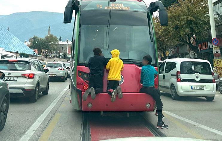 Bursa'da dört çocuk, seyir halindeki tramvayın arkasına tutunarak tehlikeli bir